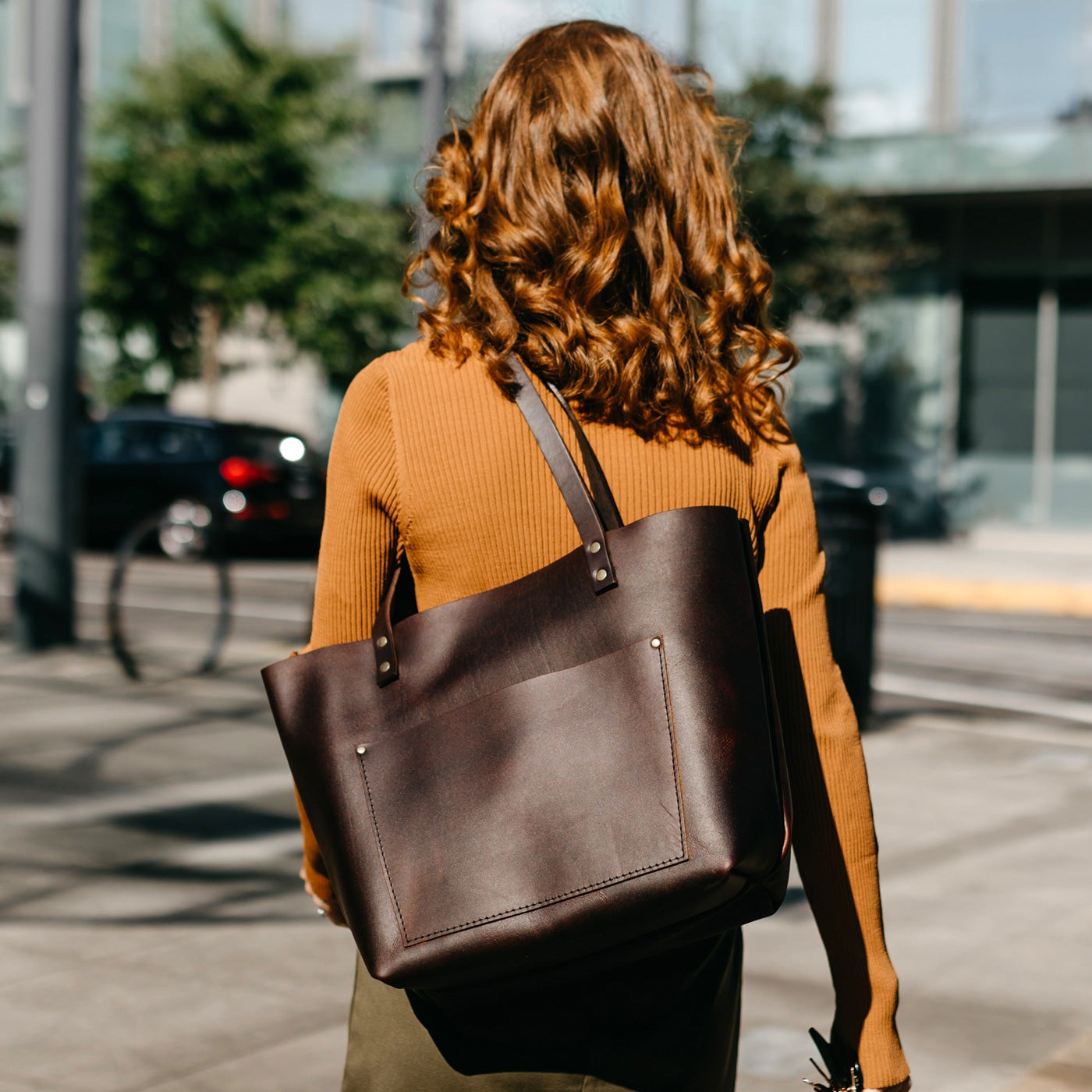 Grizzly | Model holding large leather tote bag with sturdy bridle handles and front pocket