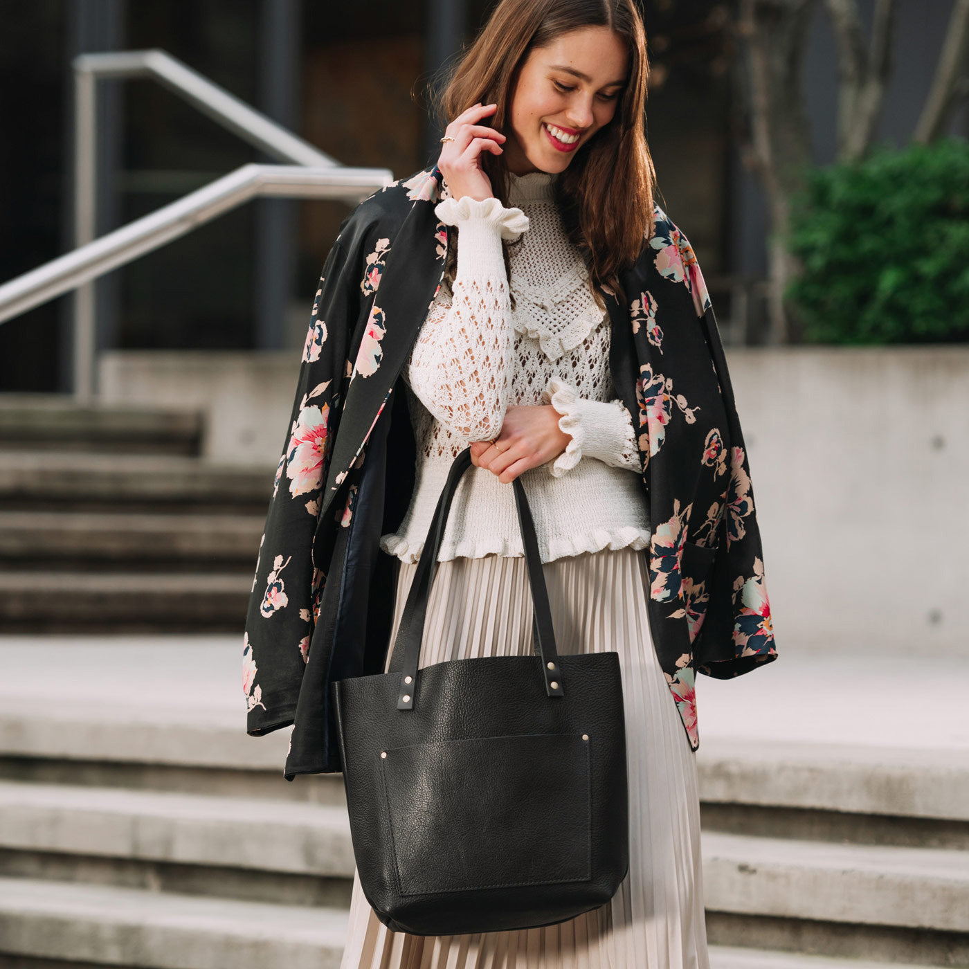 Pebbled--black | Model holding large leather tote bag with sturdy bridle handles and front pocket