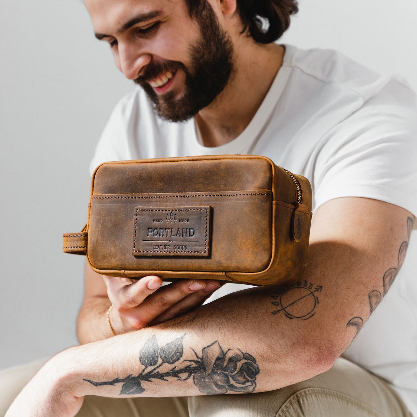 All Color: Canyon | Model holding large rectangular leather dopp kit