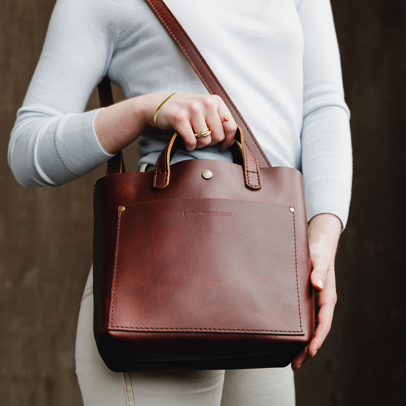 Cognac*Classic | Model holding crossbody tote bag with snap closure and front pocket