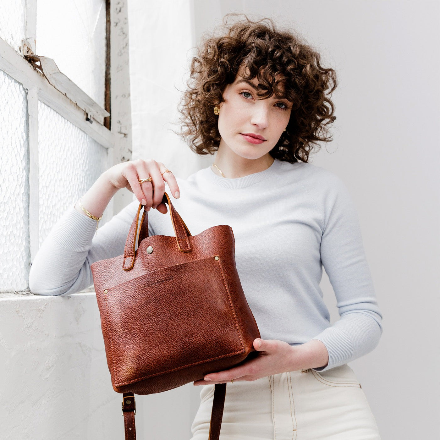 Nutmeg*Classic | Model holding crossbody tote bag with snap closure and front pocket