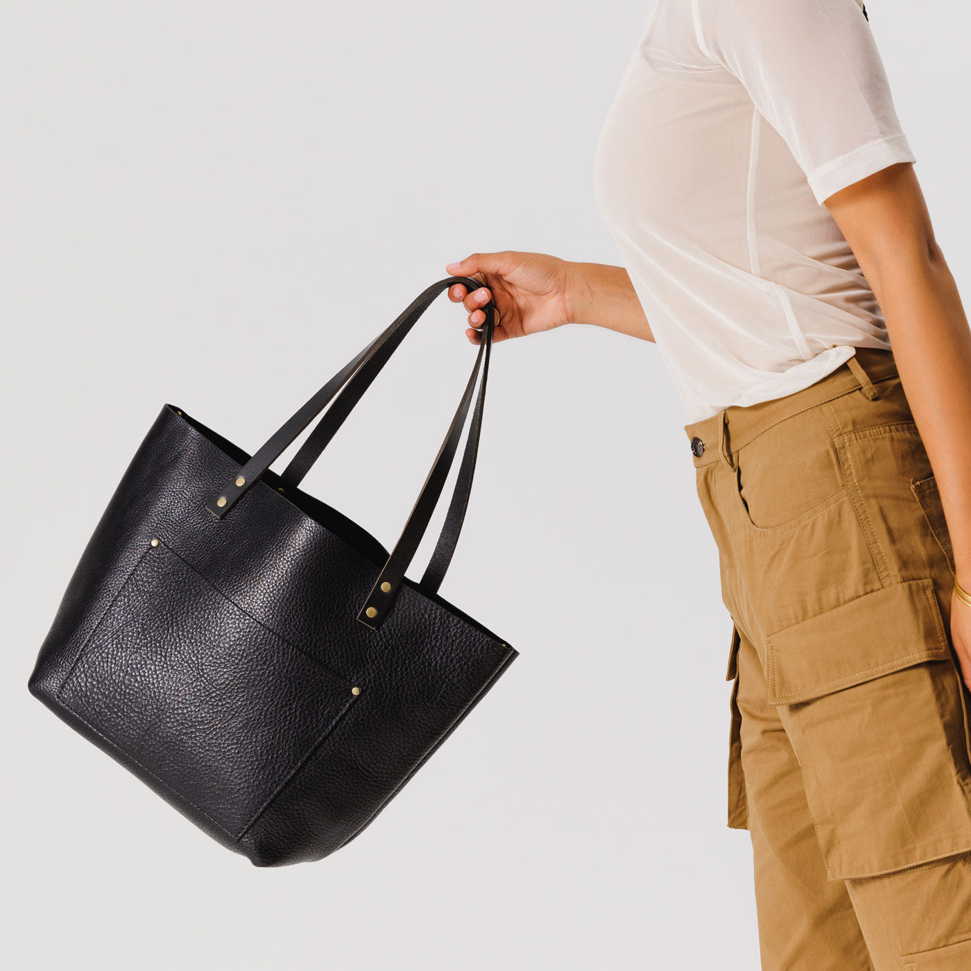 Pebbled--black*Classic | Model holding large leather tote bag with sturdy bridle handles and front pocket