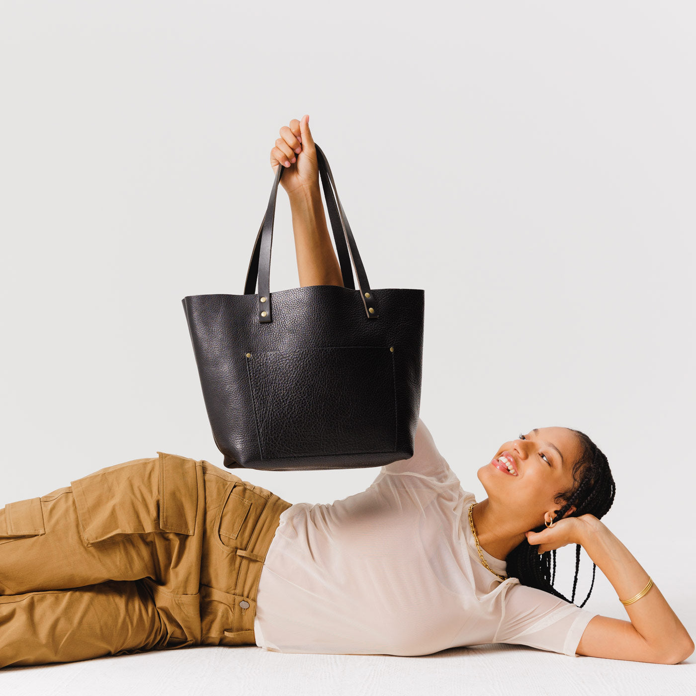 Pebbled--black Classic | Model holding large leather tote bag with sturdy bridle handles and front pocket