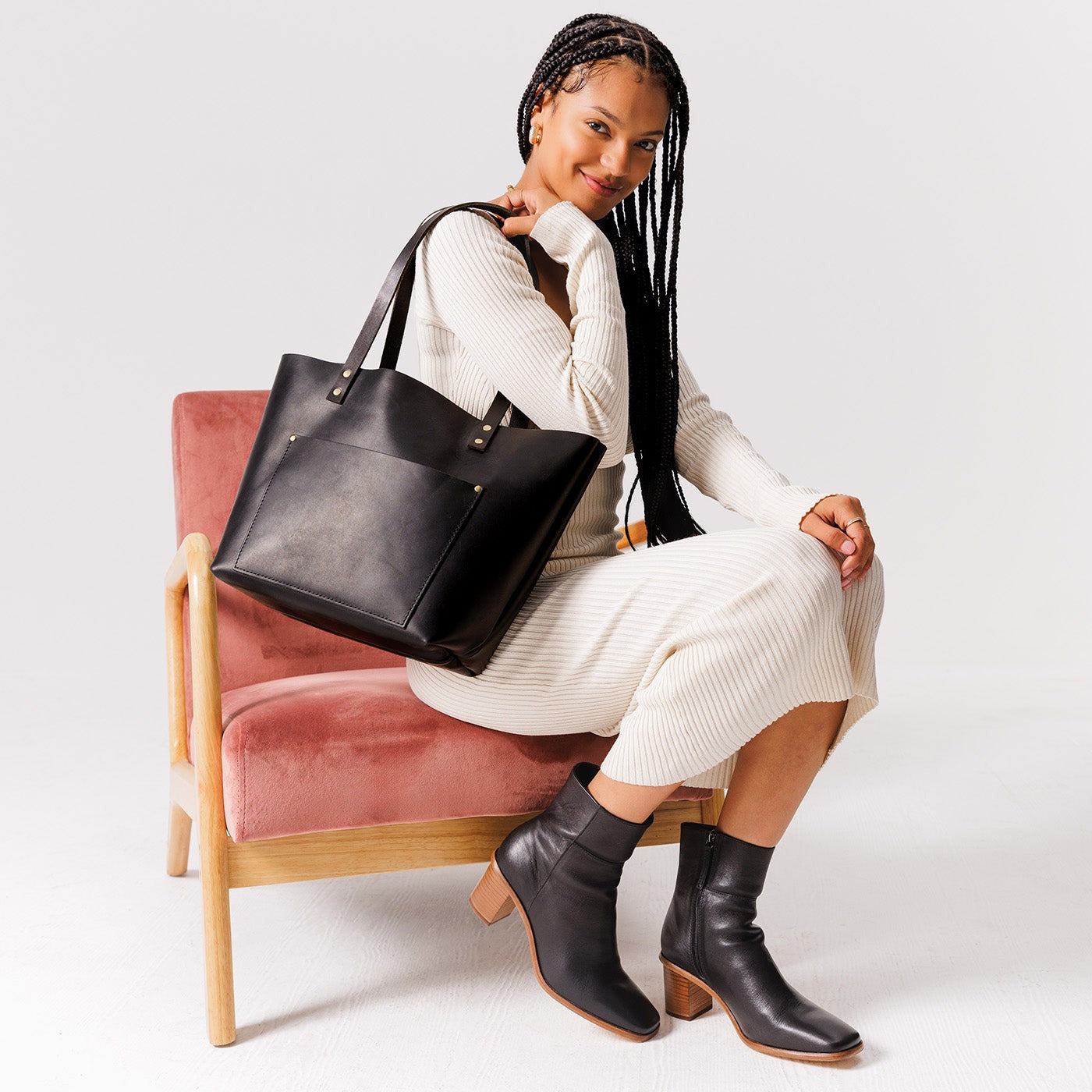 Black*Classic | Model holding large leather tote bag with sturdy bridle handles and front pocket