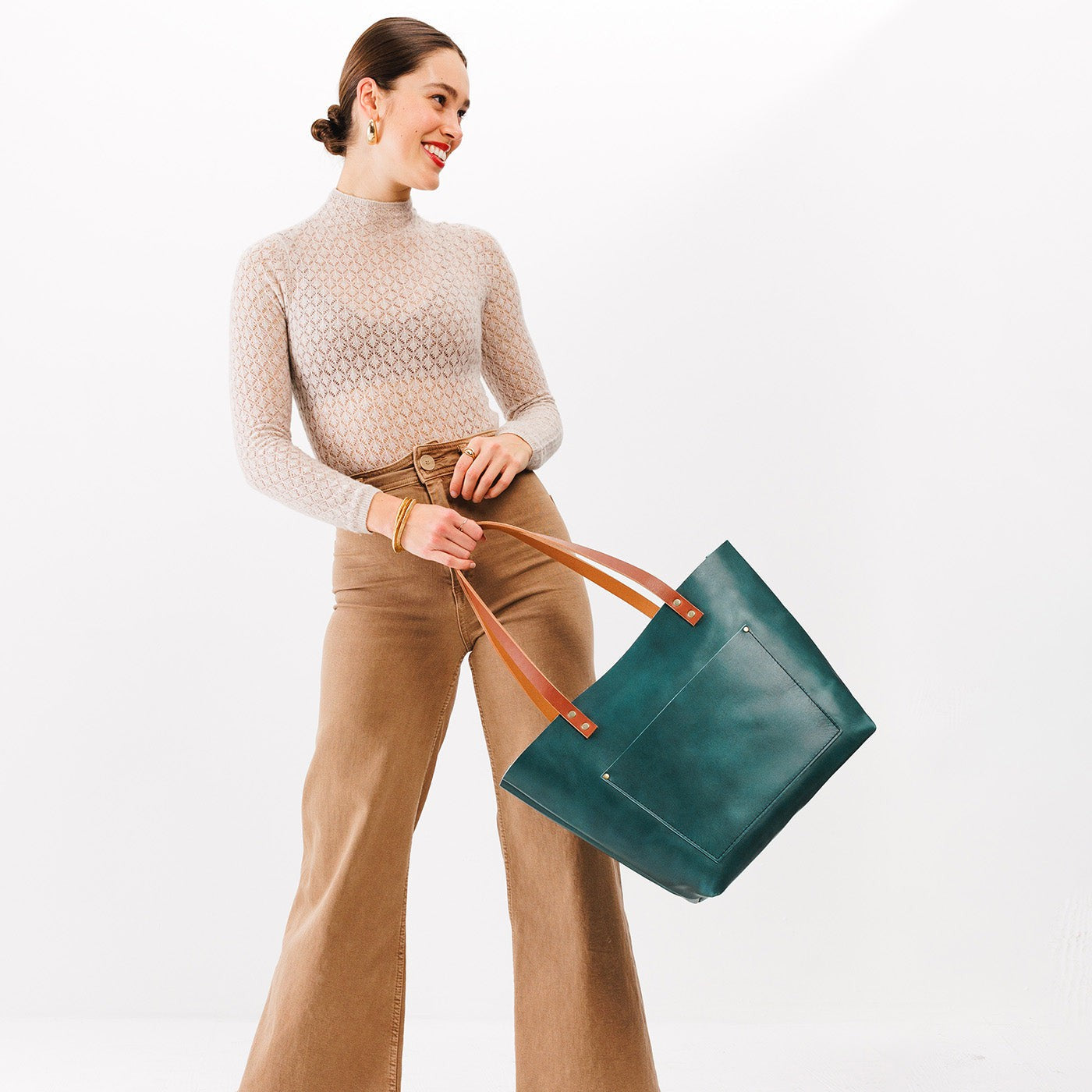 Caribbean Classic| Model holding large leather tote bag with sturdy bridle handles and front pocket