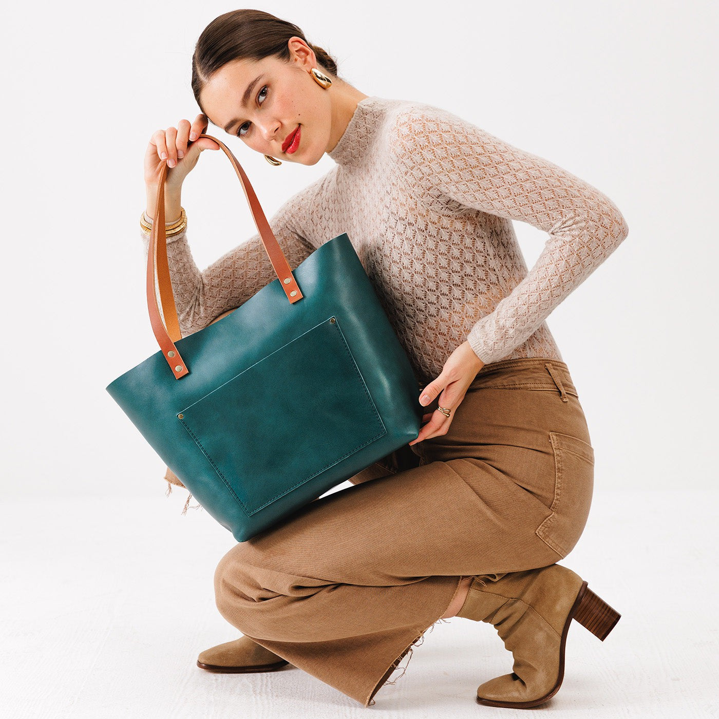 Caribbean Classic | Model holding large leather tote bag with sturdy bridle handles and front pocket  