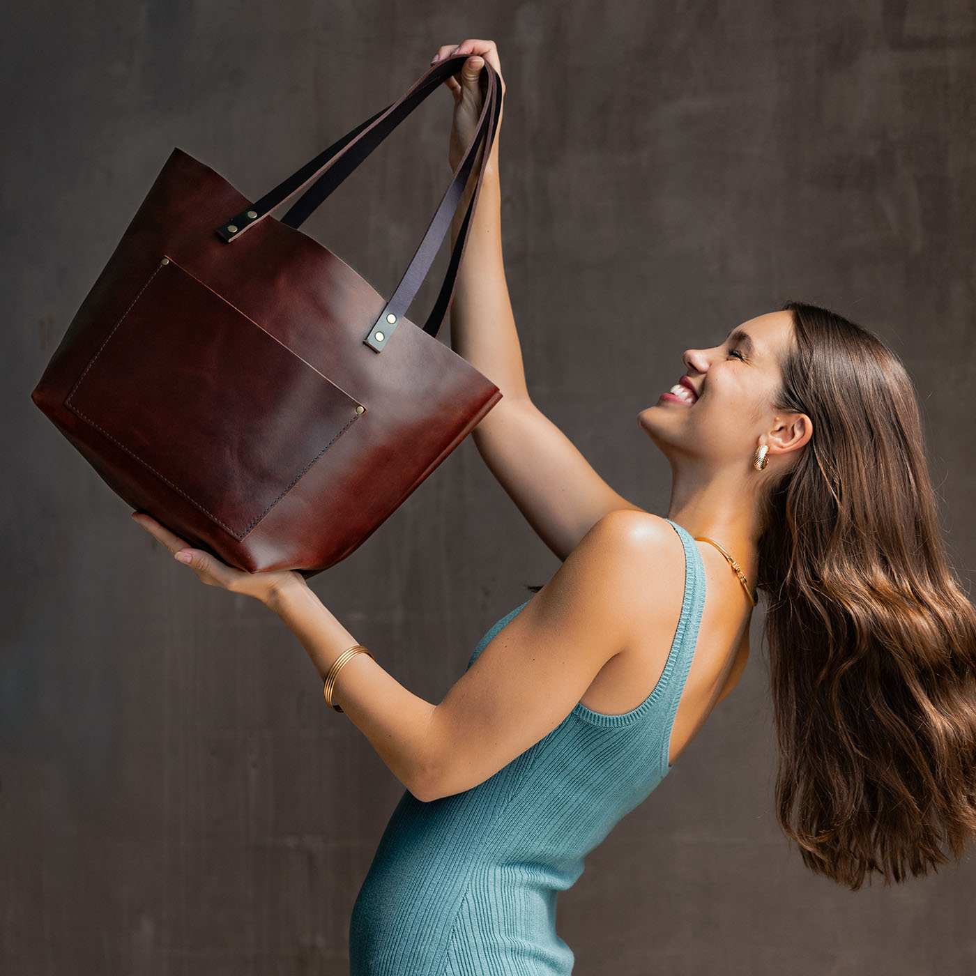 Cognac Classic | Model holding large leather tote bag with sturdy bridle handles and front pocket