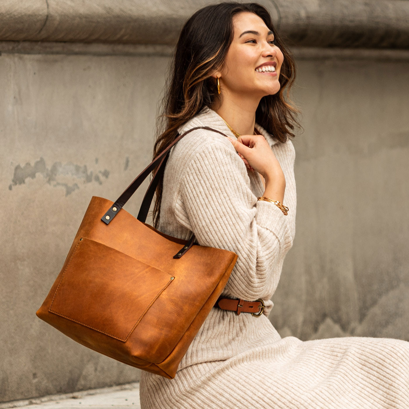 Dakota  | Model wearing larger leather tote bag with sturdy bridle handles and front pocket outside