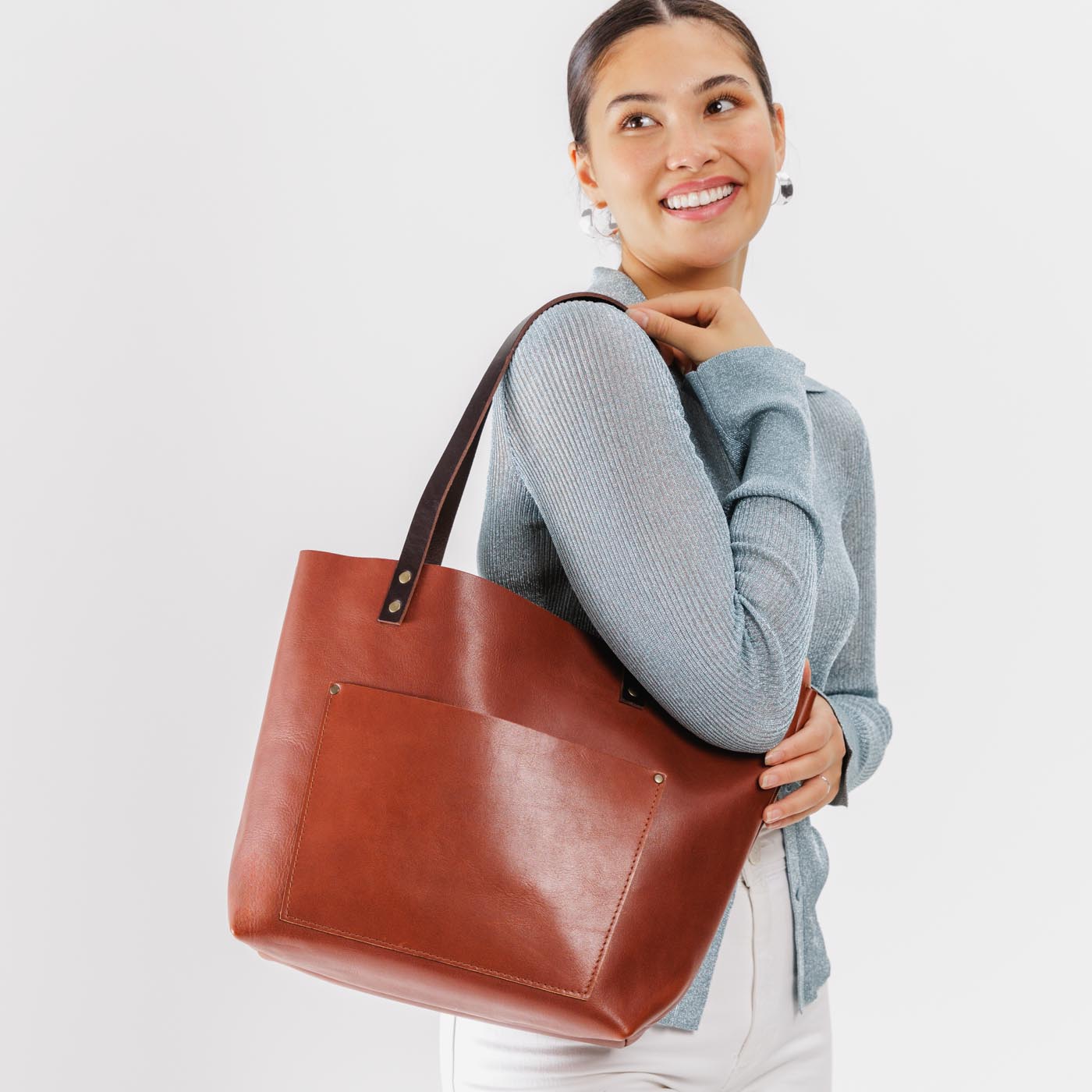 Chestnut*Classic | Model holding large leather tote bag with sturdy bridle handles and front pocket