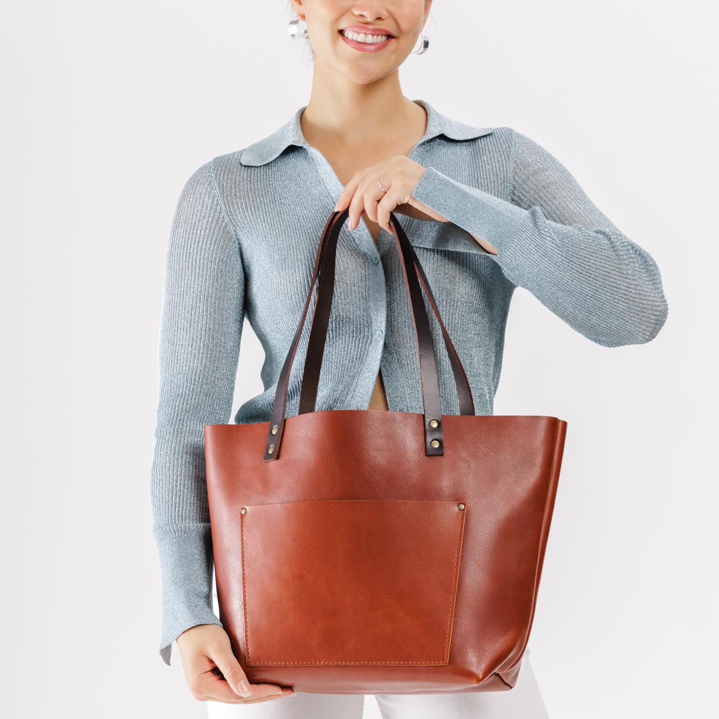 Chestnut*Classic | Model holding large leather tote bag with sturdy bridle handles and front pocket