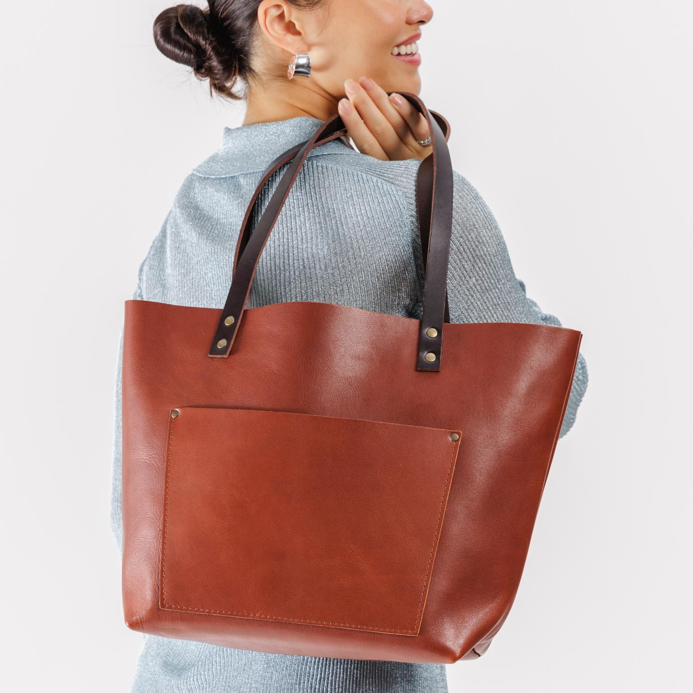 Chestnut*Classic | Model holding large leather tote bag with sturdy bridle handles and front pocket