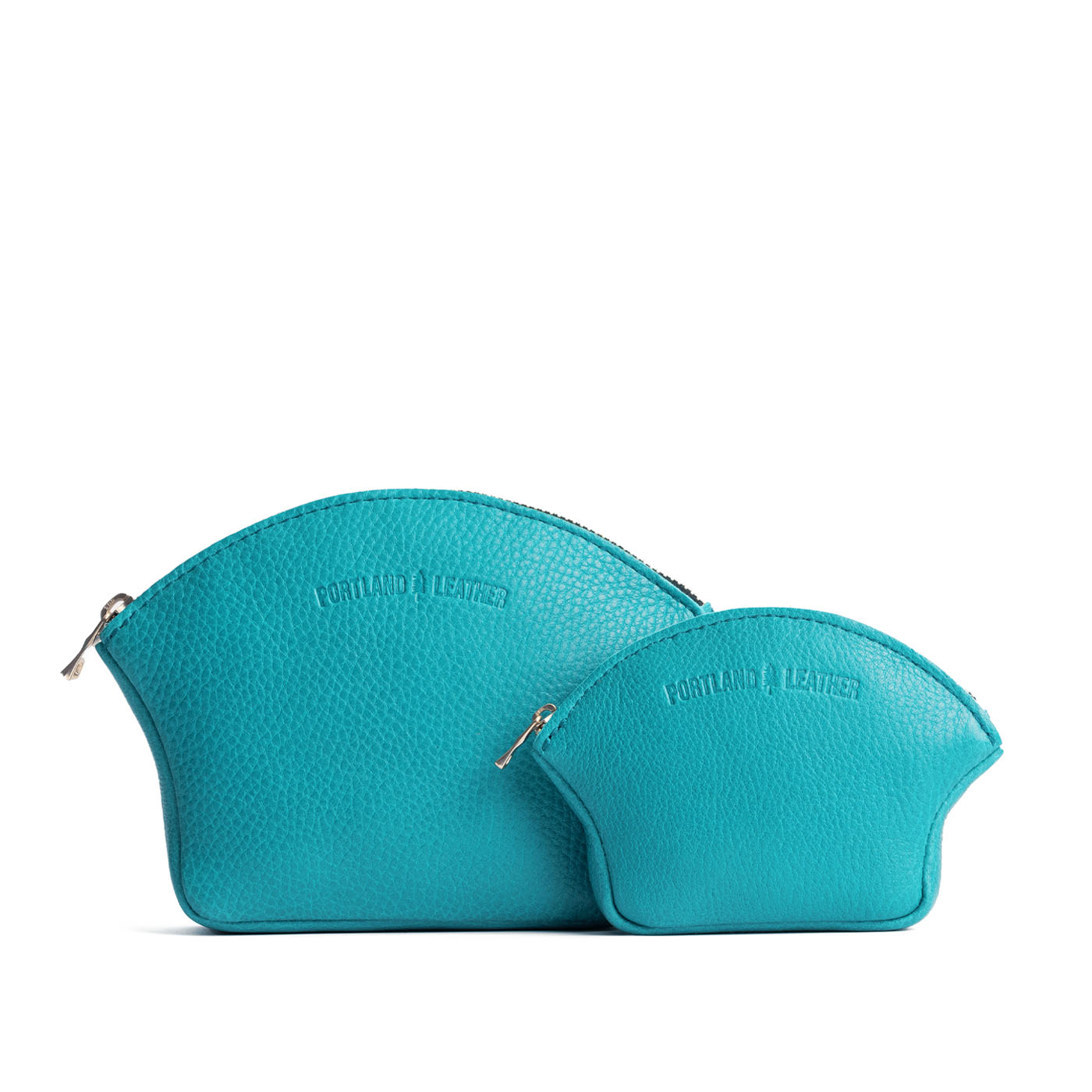 Baja | Comparison shot of small and large seashell shaped leather makeup bags with curved top zipper and flat bottom