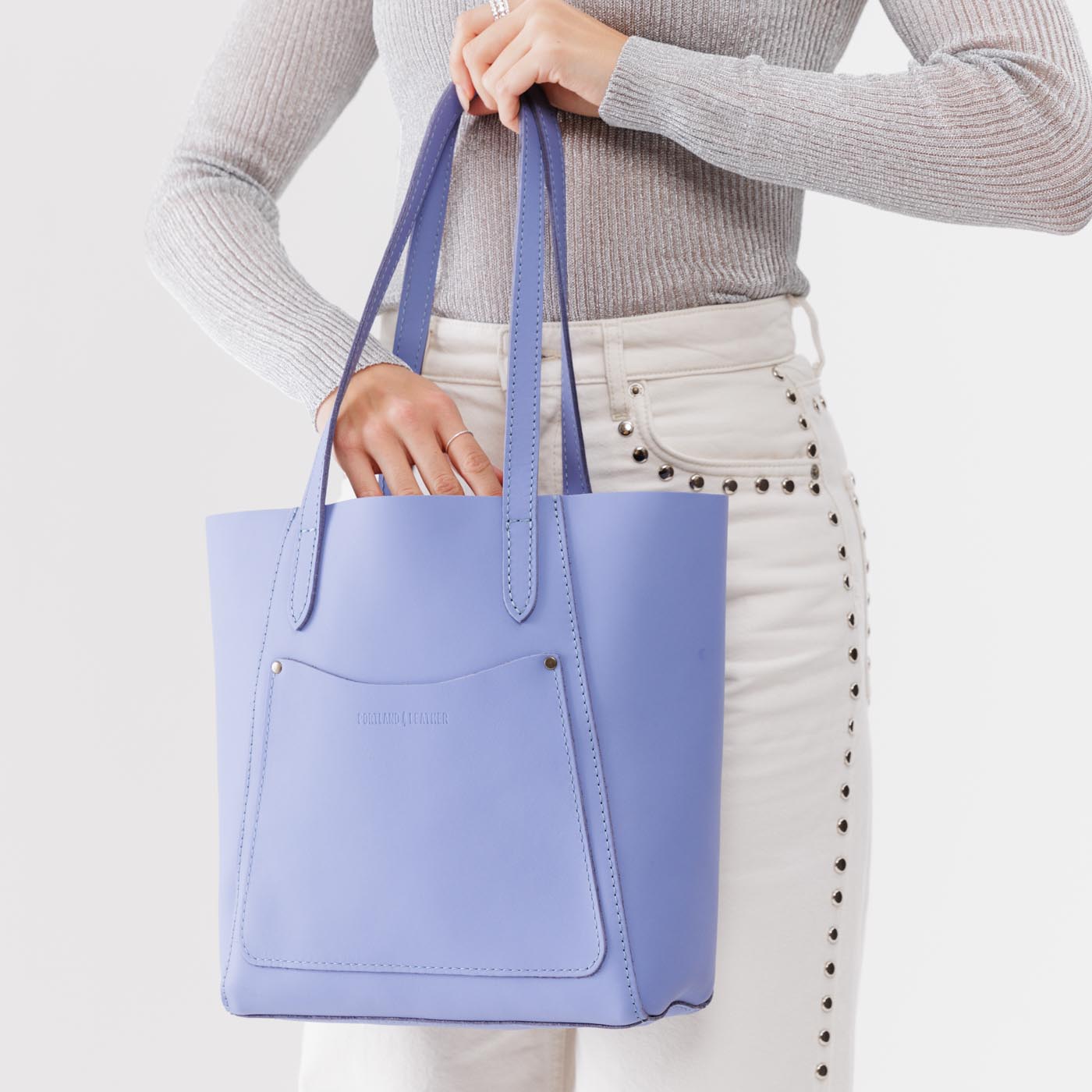 Jacaranda Large | Model holding dual shoulder strap tote bag with an exterior pocket