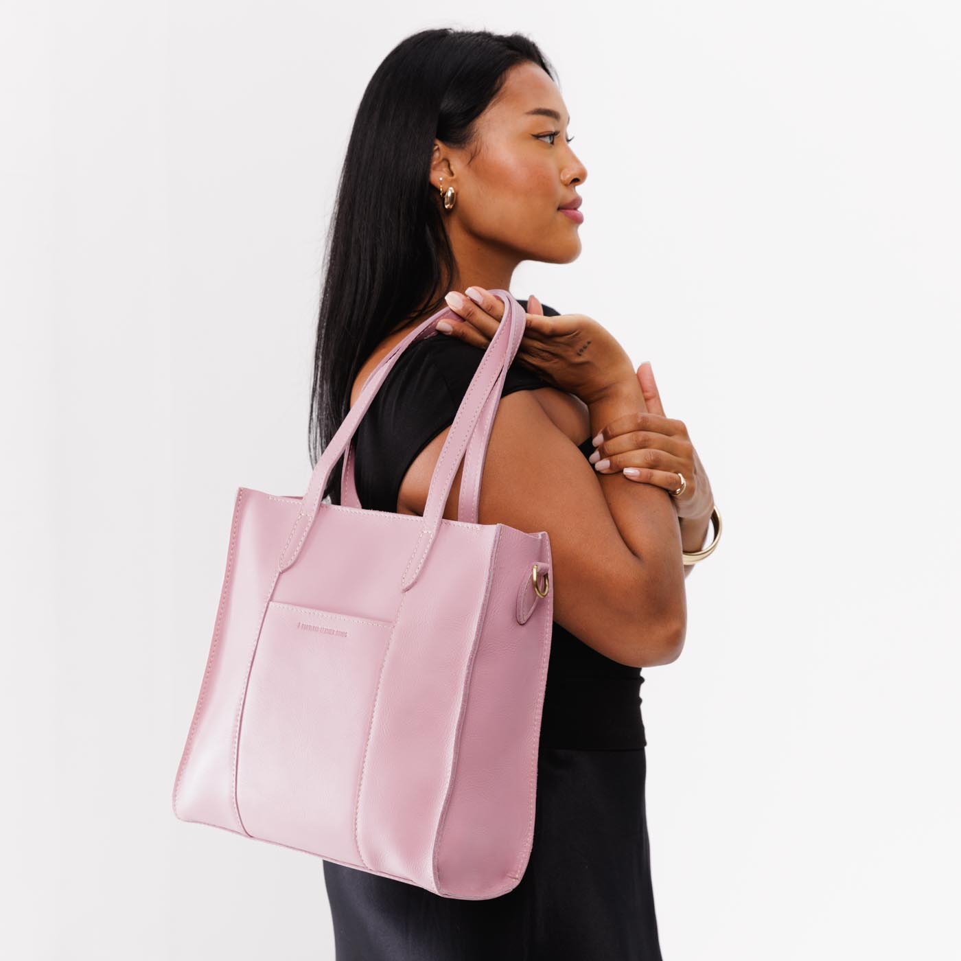 Vintage Pink*North/South | Model holding structured large tote bag with overlapping panels and crossbody strap