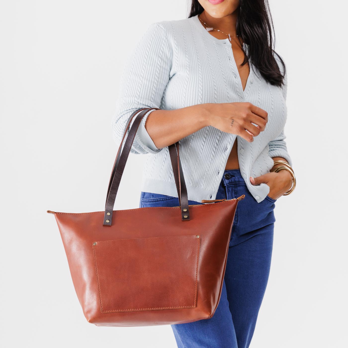 Chestnut*Zipper | Model holding large leather tote bag with sturdy bridle handles and front pocket