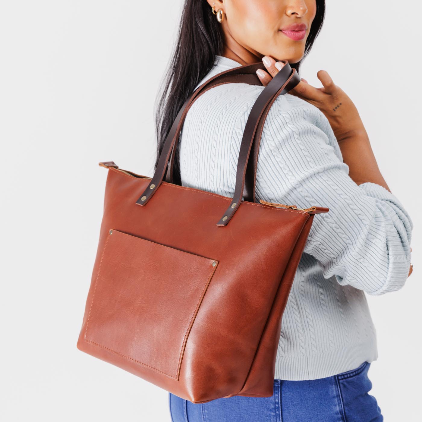 Chestnut Zipper | Model holding large leather tote bag with sturdy bridle handles and front pocket