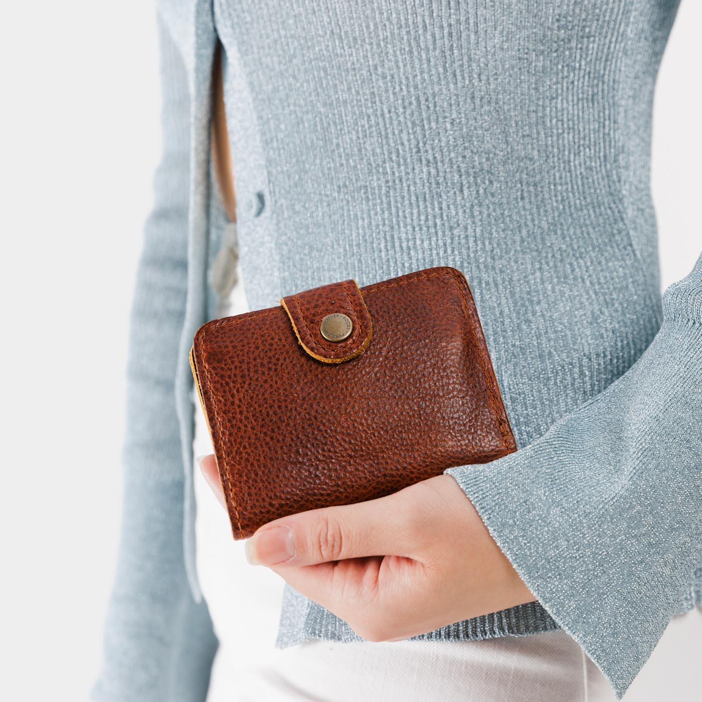 Nutmeg | Model holding small leather bifold wallet with snap closed