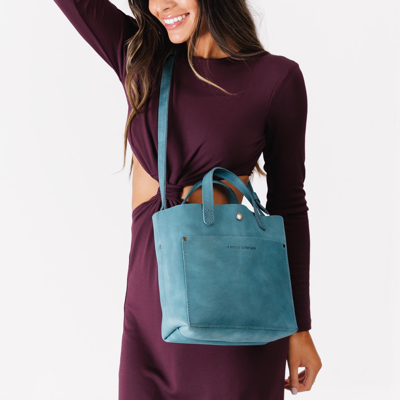 Aqua*Classic | Model holding crossbody tote bag with zipper closure and front pocket