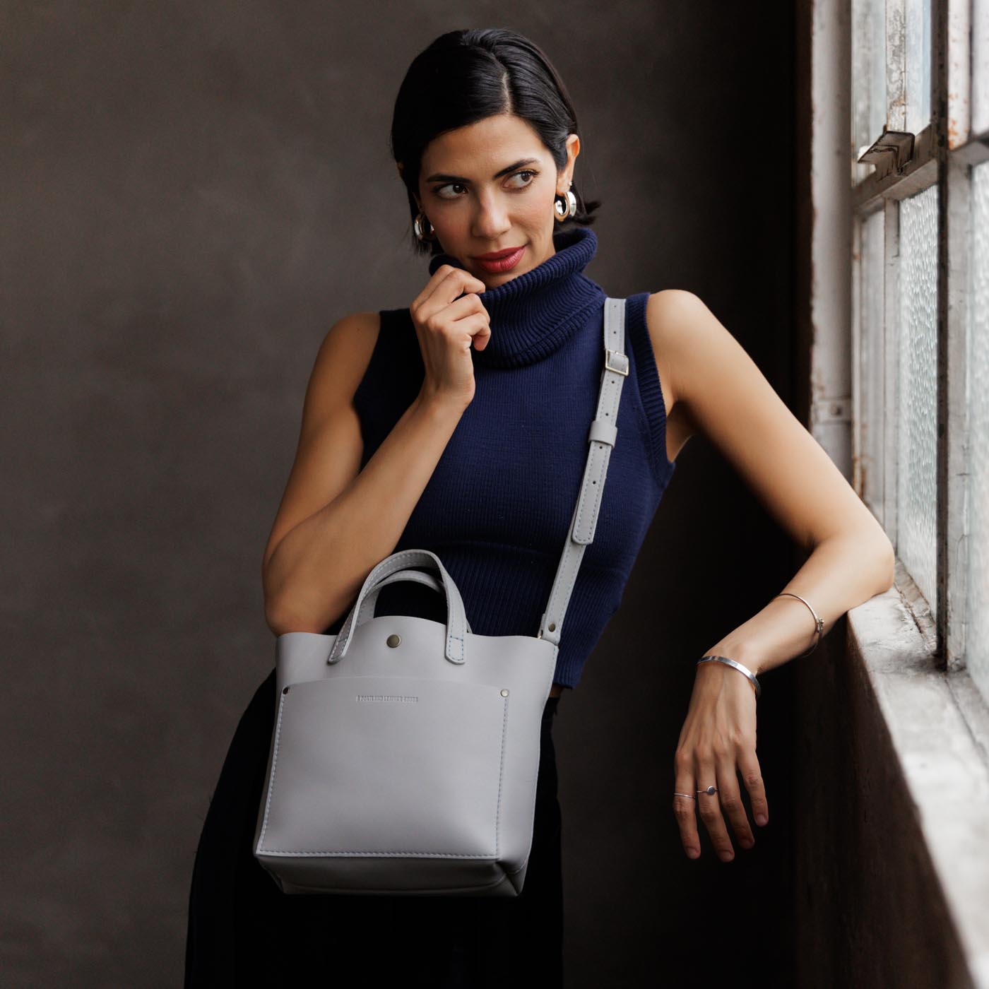 Formal Grey Classic | Model holding crossbody tote bag with snap closure and front pocket