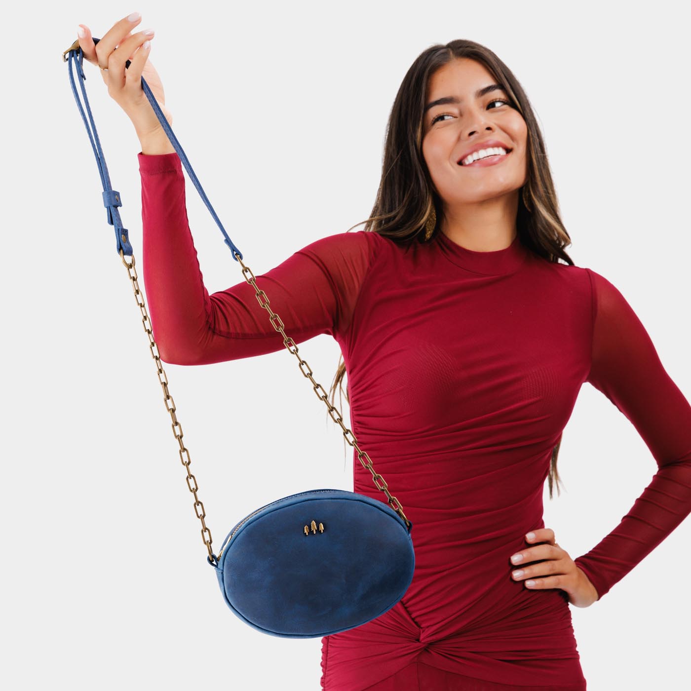 Deep Water | Model holding oval leather purse with metal crossbody chain strap and adjustable leather shoulder guard