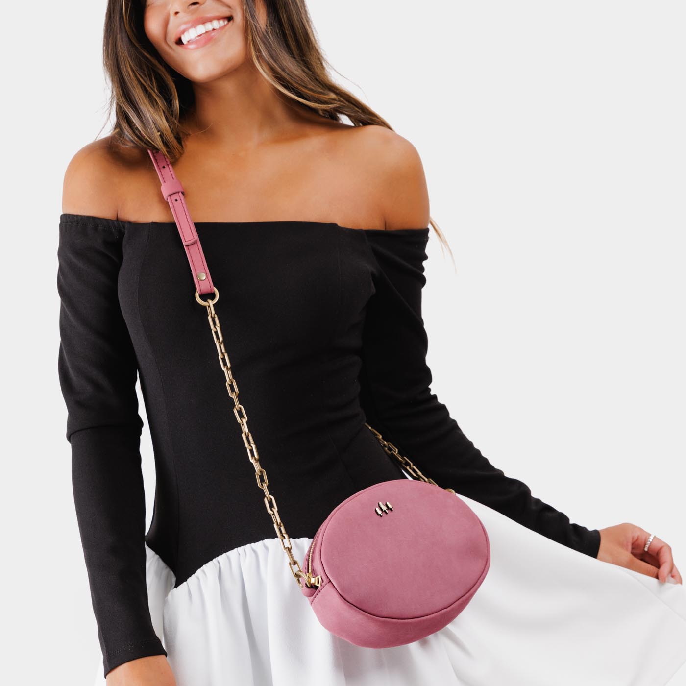 Foxglove | Model wearing oval leather purse with metal crossbody chain strap and adjustable leather shoulder guard