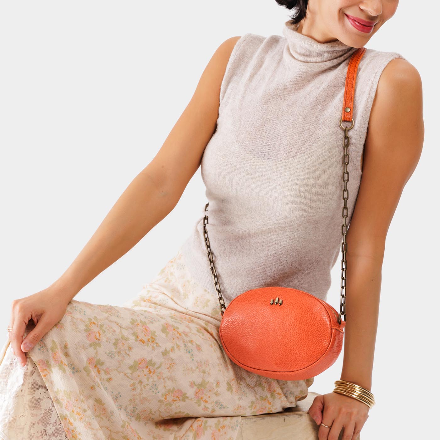 Koi | Model wearing oval leather purse with metal crossbody chain strap and adjustable leather shoulder guard