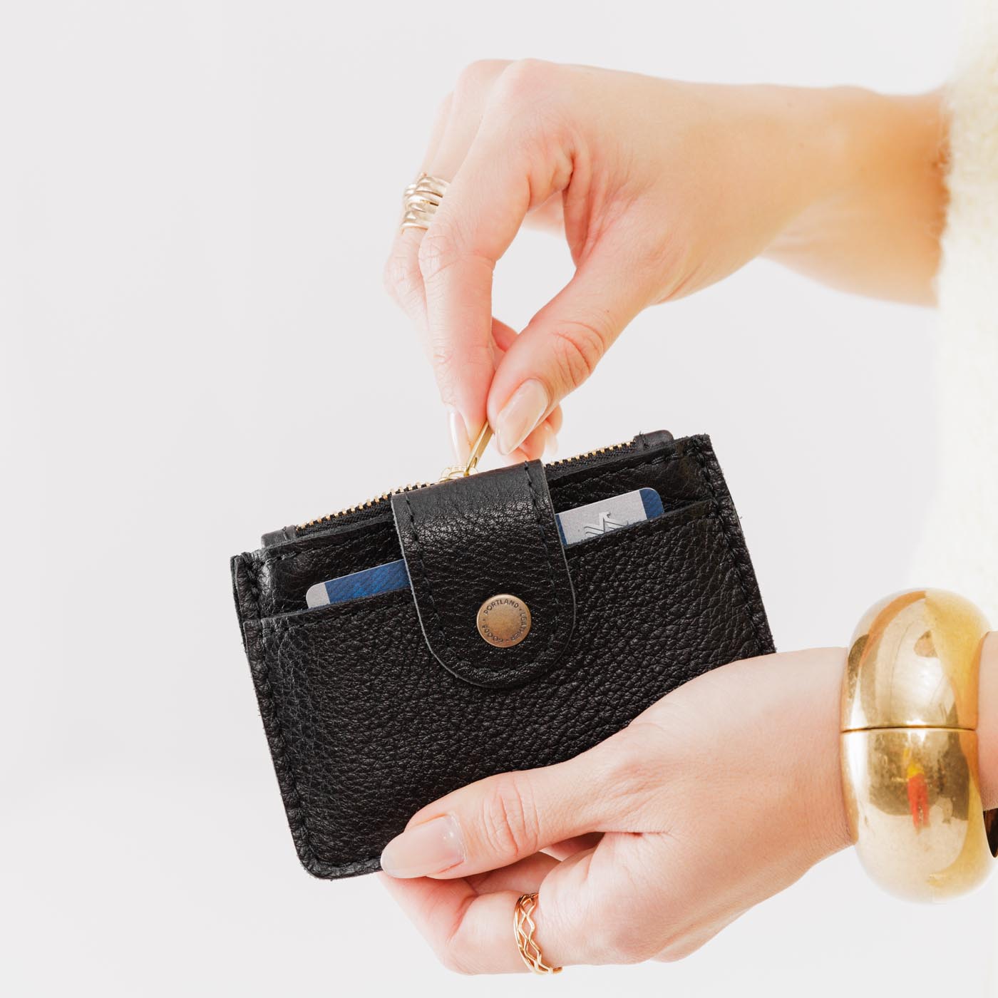 Pebbled--black | Model holding compact wallet with snap closure and zippered pouch