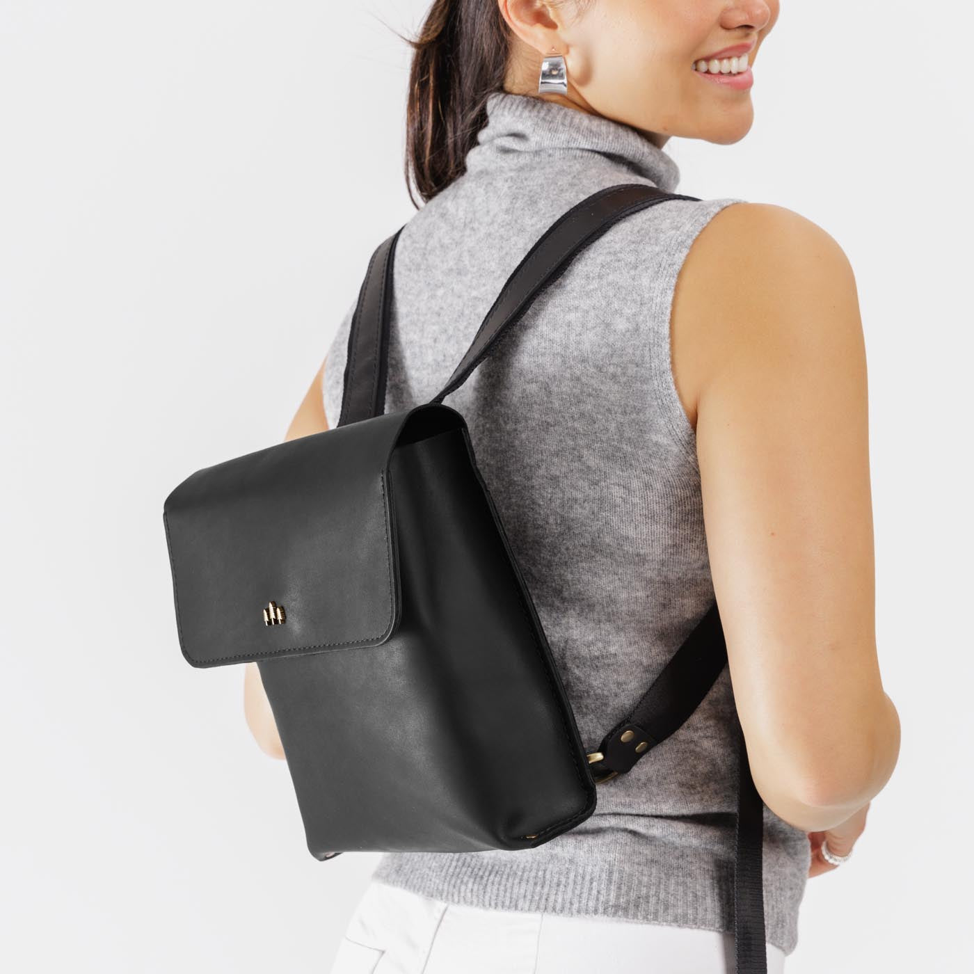 Black | Model wearing rectangular backpack with leather lined nylon straps and magnetic flap closure