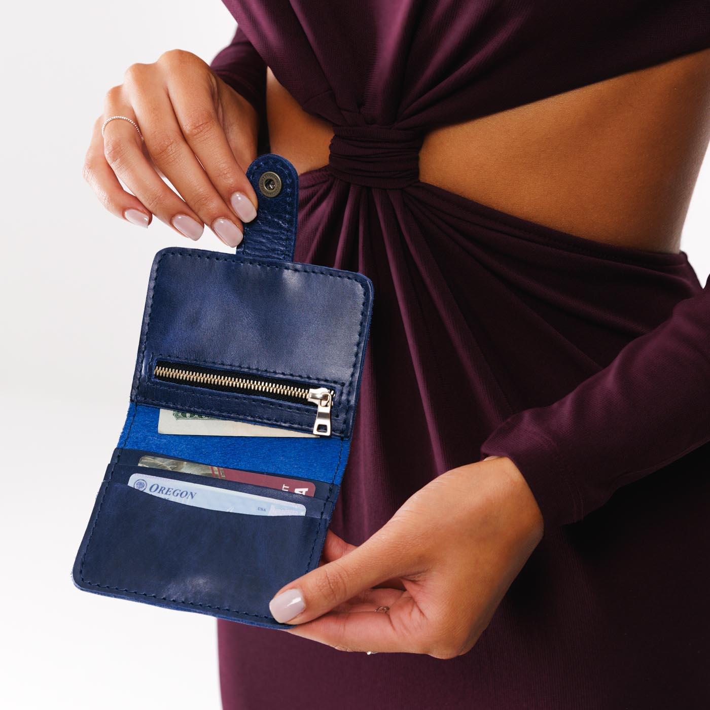 Cowboy Blue | Model holding small leather bifold wallet with snap open