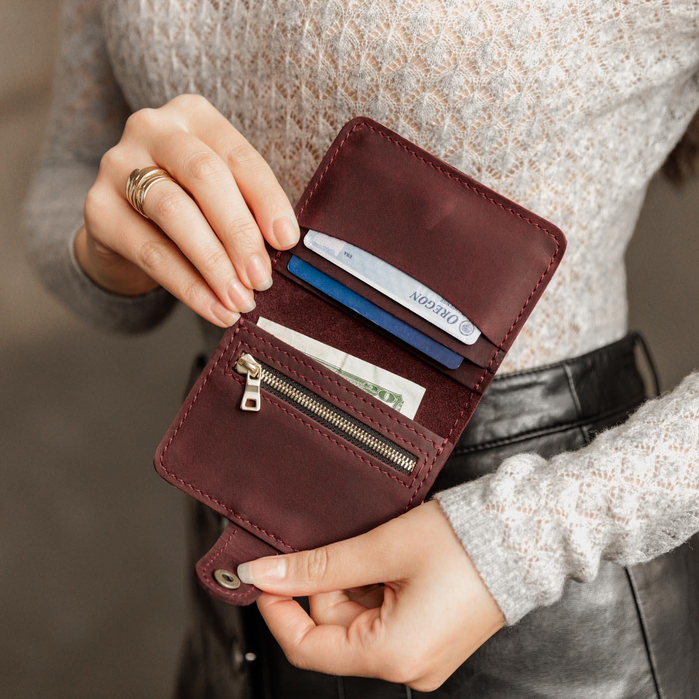 Merlot | Model holding small leather bifold wallet with snap open