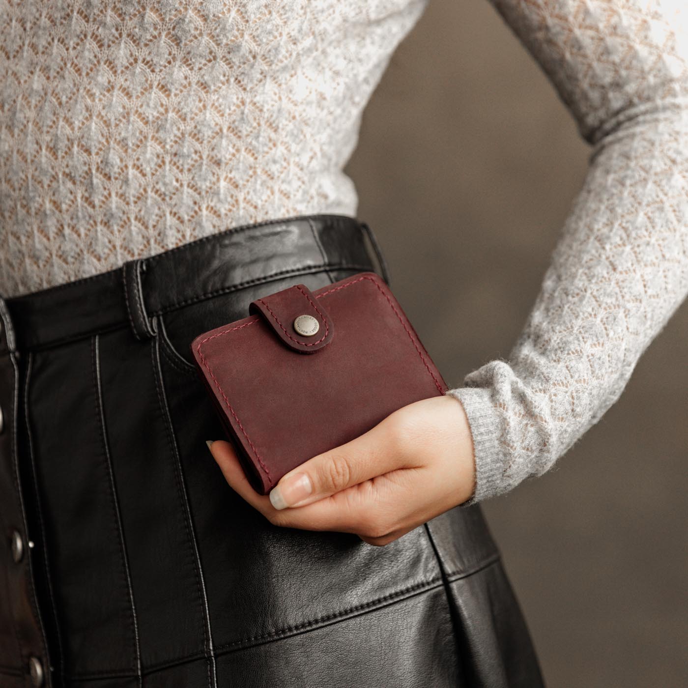 Merlot | Model holding small leather bifold wallet with snap closed