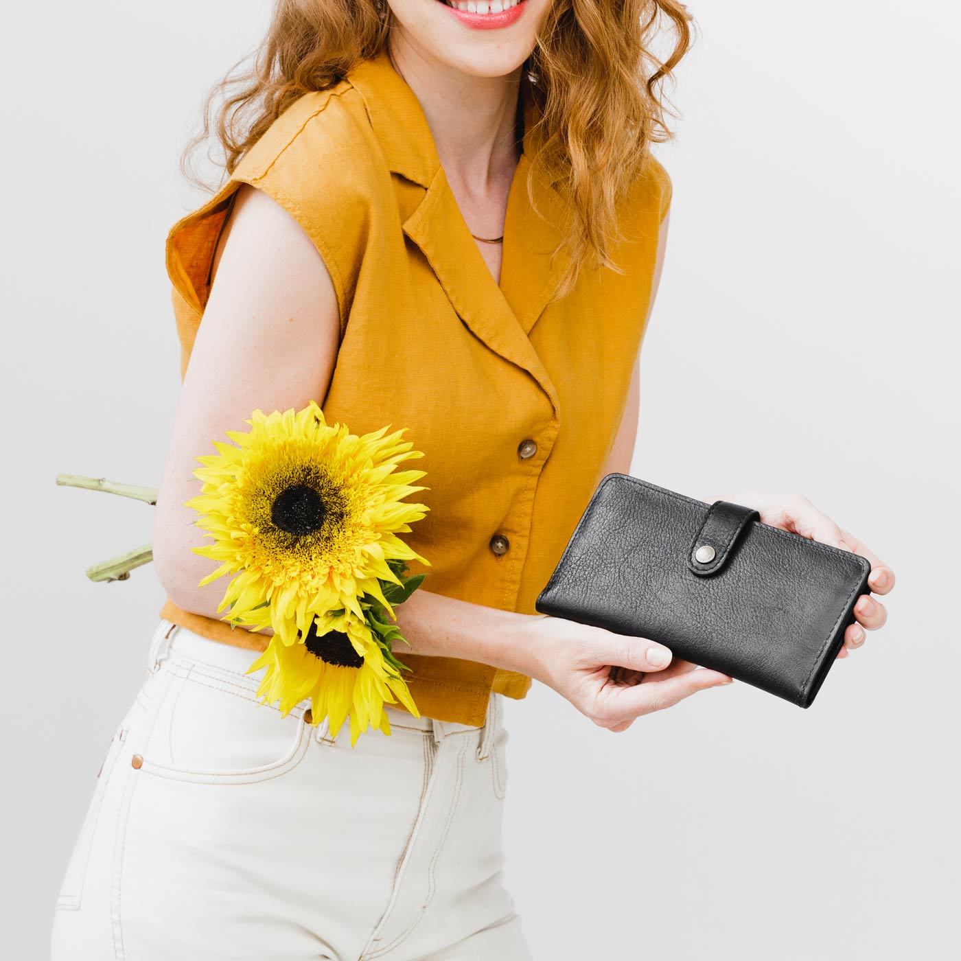 Pebbled--black | Model holding flowers and leather wallet with snap closed