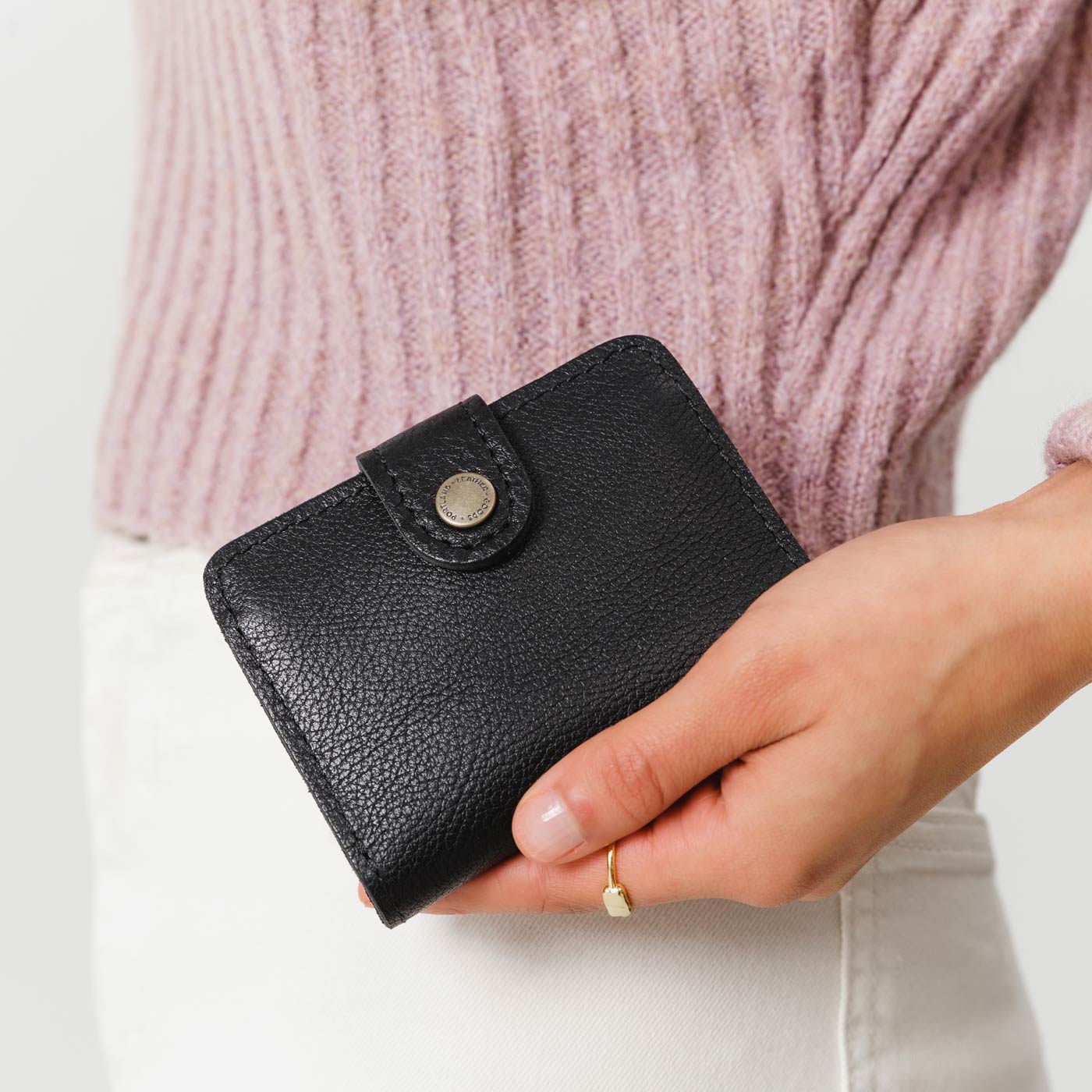 Pebbled--black | Model holding small leather bifold wallet with snap closed