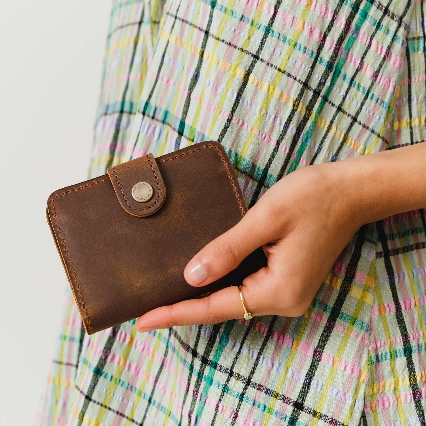 Canyon | Model holding small leather bifold wallet with snap closed