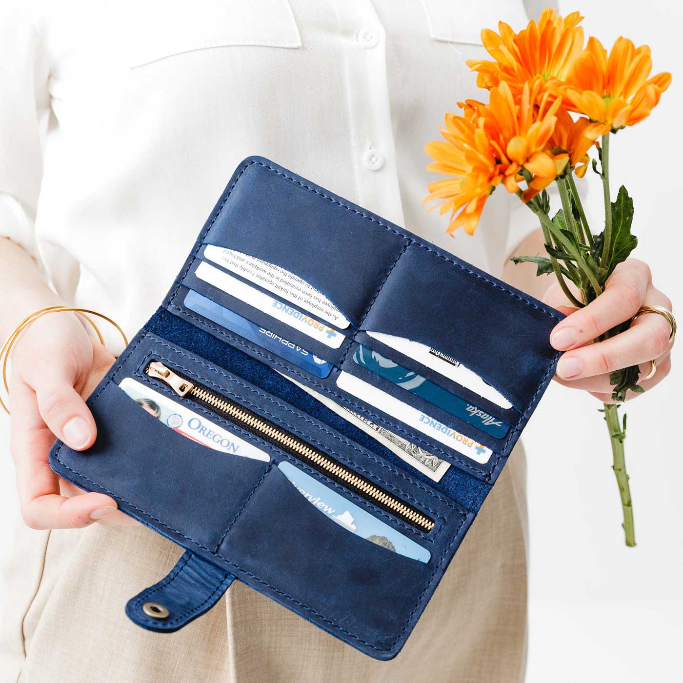 Deep Water | Model holding flowers and leather wallet with snap open