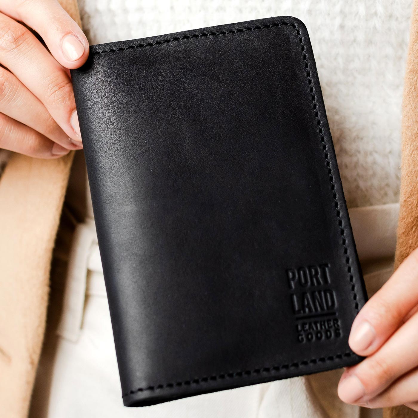 Black | Model holding leather passport case with PLG logo